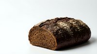 Dark rye bread loaf with seeds and grains on white background, artisan bakery product for healthy eating and nutrition concepts.