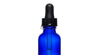 Cobalt blue glass dropper bottle with black pipette cap isolated on white background for skincare, essential oils, serums, and cosmetic product packaging design.