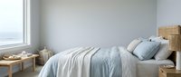 Serene bedroom interior with unmade bed, soft linens, wooden nightstands, and natural light from large window, suitable for home decor and lifestyle design projects.