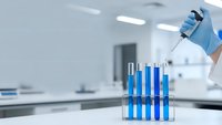 Laboratory scientist in blue gloves conducting chemical analysis with test tubes containing blue solutions in modern research facility.