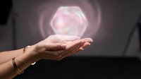 Hands holding glowing hexagonal geometric shape with pink light energy, isolated on dark background for technology and innovation concepts.