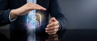 Businessman hands protecting glowing user profile with security lock icon on digital interface representing data privacy and cybersecurity protection.