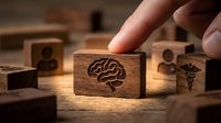 Hand holding wooden stamp with brain symbol among medical and healthcare stamps on wooden surface, representing healthcare innovation, medical research, and professional services for business and design projects.