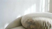 Soft beige fabric armchair detail in bright natural light creating peaceful minimalist interior atmosphere for home decor and furniture design concepts.