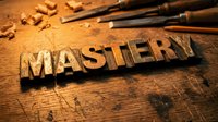 Wooden letter blocks spelling MASTERY on rustic workbench with carving tools and wood shavings, representing craftsmanship and skill development.