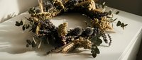 Rustic autumn wreath with dried flowers, wheat stalks and natural elements on white wooden surface for seasonal home decor and harvest celebrations.