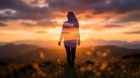 Young woman silhouette standing on mountain peak during golden sunset with dramatic orange sky and rolling hills landscape for inspiration concepts.
