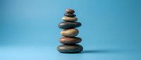 Balanced stack of smooth river stones creating zen meditation tower on blue background for wellness and mindfulness concepts.