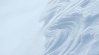 Close-up of swirling snow patterns and wind-carved textures on white winter surface, suitable for backgrounds and seasonal design projects.