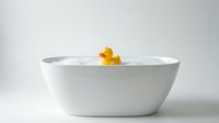 Yellow rubber duck floating in white bathtub on clean background for bathroom decor and childcare concepts.