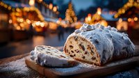 Traditional Christmas stollen cake with powdered sugar on wooden board at festive holiday market with warm bokeh lights and decorated Christmas trees in background.