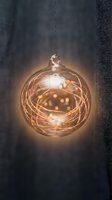Hanging glass ornament filled with warm golden fairy lights and copper wire, glowing against dark textured background for holiday and festive decoration projects.