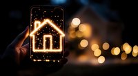 Glowing house icon on smartphone screen with bokeh lights in background, representing smart home technology and digital real estate solutions.