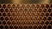 Copper pipes arranged in geometric pattern creating industrial texture background for construction and plumbing projects.