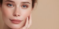 Young Caucasian woman with natural makeup touching face gently, showcasing healthy glowing skin and beauty routine for skincare and cosmetic products.