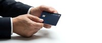 Male hand in dark business sleeve holding dark blue credit card against white background for financial transaction concepts.