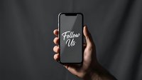 Hand holding a smartphone with Follow Us text on screen, social media marketing concept on dark background.