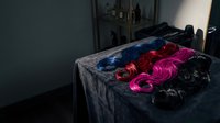 Colorful wigs arranged on dark velvet fabric table, featuring blue, red, pink, and black synthetic hair pieces for costume, theater, cosplay, and fashion styling purposes.