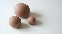 Three matte beige spheres of different sizes arranged on white background for modern minimalist design and contemporary decor projects.