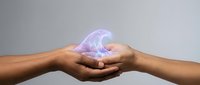 Cupped hands holding glowing purple energy orb with ethereal light effects against neutral background for spiritual healing and wellness concepts.
