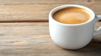 Fresh coffee with golden crema in white ceramic cup on rustic wooden table background, morning beverage with copy space for cafe menu design.