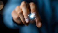 Glowing magical sparkle effect between fingers in dark background, mysterious light particles and bokeh creating ethereal atmosphere for fantasy and magical concepts.