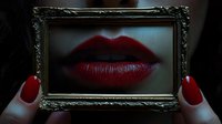 Red lips in ornate vintage frame held by hands with matching nail polish creating artistic beauty concept for makeup and cosmetics advertising.