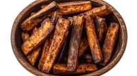 Crispy baked sweet potato wedges seasoned with spices in rustic wooden bowl, overhead view showing golden brown caramelized edges and crispy texture.