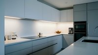 Modern minimalist kitchen interior with sleek gray cabinets, white countertops and integrated appliances for contemporary home design and renovation projects.