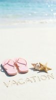 Pink flip flops, starfish, and seashell on white sand with vacation written, turquoise ocean waves in background, summer holiday concept.