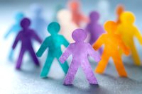 Colorful paper cutout figures holding hands in circle formation on light background, symbolizing unity, teamwork and social connection in community.