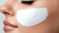 Young woman applying white facial mask cream on cheek for skincare routine and beauty treatment in spa wellness concept.