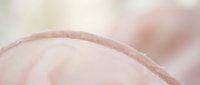 Close-up macro shot of smooth human skin texture with natural pink tones and soft lighting, showing detailed surface patterns for skincare and beauty concepts.