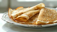 Freshly made thin crepes or pancakes with sugar served on vintage porcelain plate, close up view in natural daylight. Traditional homemade breakfast.