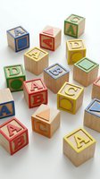Colorful wooden alphabet blocks with letters and shapes scattered on white background for educational toys and children learning activities.