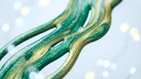 Abstract flowing green and gold ribbons with glittery texture against soft bokeh lights background for luxury design projects and festive decorations.