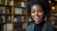 Young African American woman with natural curly hair and bright smile wearing black turtleneck in library setting with soft bokeh lighting, radiating confidence and warmth.