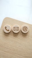 Wooden contact buttons with phone, email, and message icons on natural wood surface for business communication and customer service concepts.