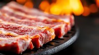 Grilled beef steaks sizzling on cast iron skillet with flames in background, perfect for restaurant menus, cooking blogs, and food marketing materials.