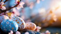 Decorated Easter eggs with gold speckles and pastel patterns nestled among blooming cherry blossoms against soft blurred background, creating festive spring atmosphere.