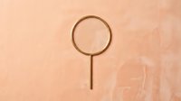 Magnifying glass with circular lens and long handle isolated on warm beige textured background, suitable for search, investigation, and detective design projects.