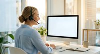 Professional woman with headset working at computer in modern office environment for customer service and remote work applications.