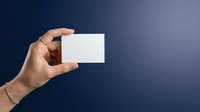 Female hand holding a blank white card against a dark blue background, copy space for text or branding mockup design.