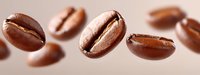 Fresh roasted coffee beans floating in soft focus on pink background, macro photography showing rich brown color and natural texture of arabica beans.