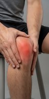 Man holding painful inflamed knee with red highlighted area showing joint pain and arthritis symptoms for medical healthcare concepts.