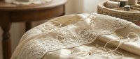 Delicate ivory lace fabric with intricate floral embroidery draped elegantly, showcasing detailed needlework and vintage textile craftsmanship for wedding, fashion, and design projects.