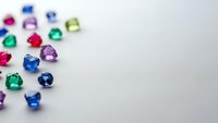 Colorful precious gemstones scattered on white background with copy space for jewelry design and luxury accessories marketing materials.