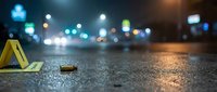 Crime scene evidence marker on wet asphalt street at night with blurred city lights and police investigation backdrop for forensic documentation.