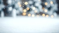 Winter snow surface with blurred bokeh lights and falling snowflakes creating magical holiday atmosphere for seasonal marketing and festive designs.