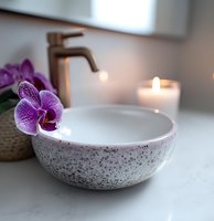 Modern bathroom sink with bronze faucet, purple orchid flower and glowing candle on marble countertop creates serene spa atmosphere for wellness and relaxation.